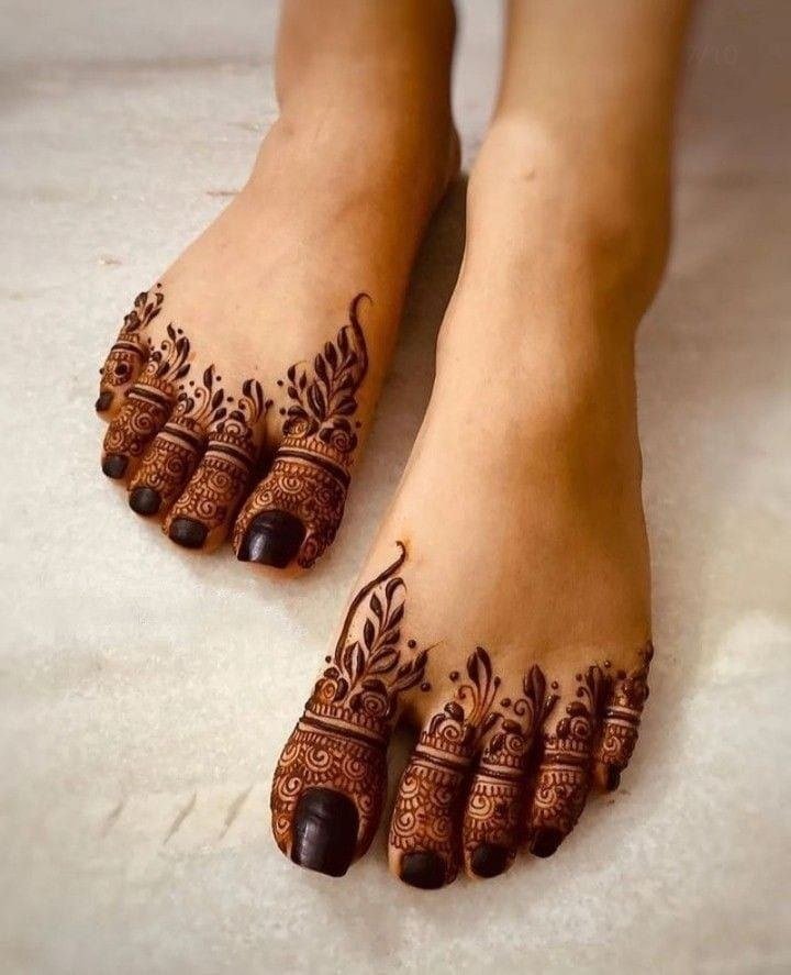 Feet with dark floral and leafy mehndi concentrated around the toes and upper foot