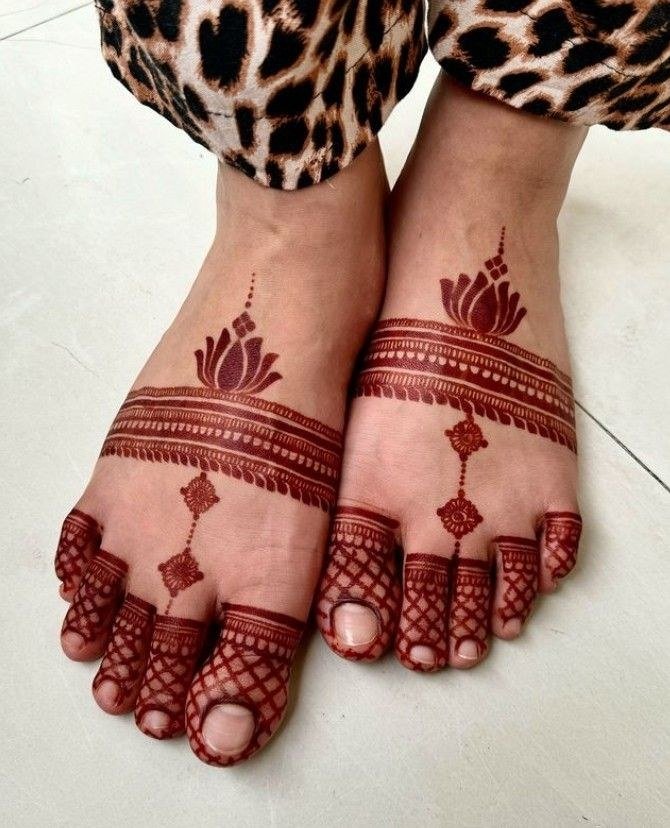 Feet with simple reddish mehndi bands across the upper foot, small hanging motifs and geometric toe details